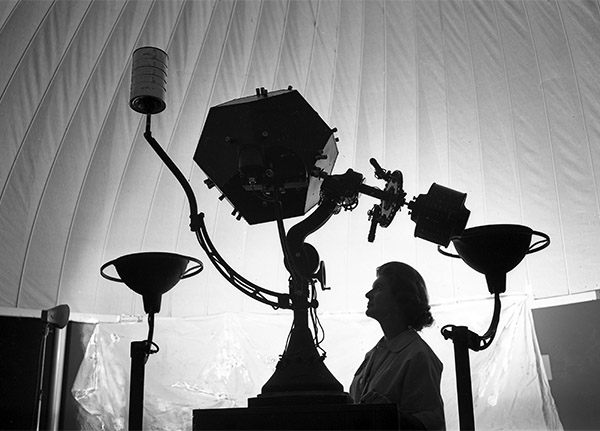 The silhouette of a woman standing with the original planetarium projector