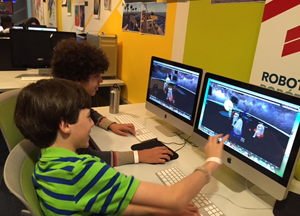 Two young boys compare computer screens to discuss their virtual simulations.