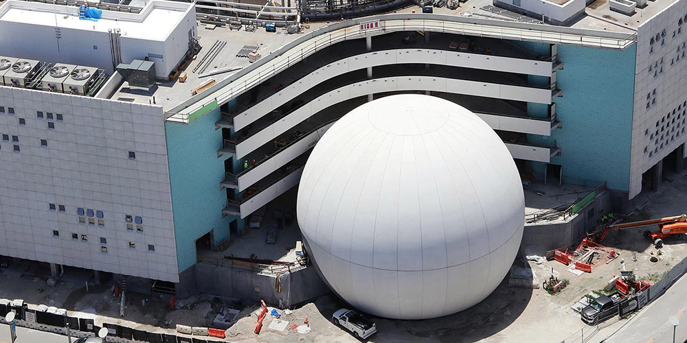 The white exterior of the finished planetarium shines in the sunlight.