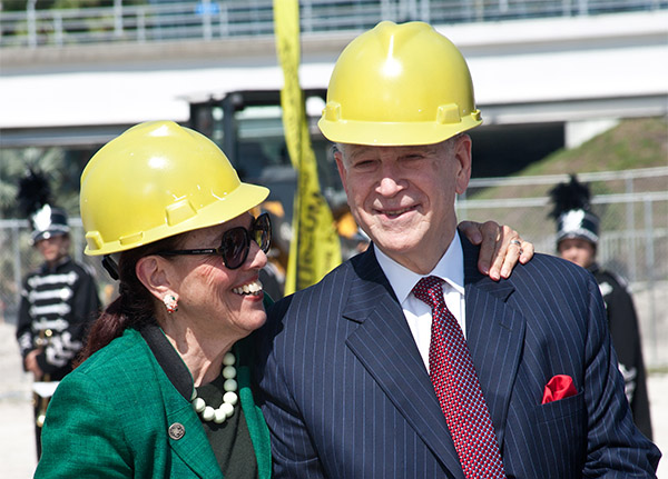 Dr. Phillip Frost and Patricia Frost pose happily in yellow hard hats at the new museum construction site.