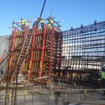 Hose from pump truck pouring concrete into the forms in the planetarium (steel reinforcement bars can be seen in place)