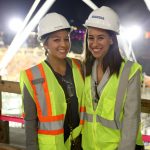 Adults posing for a photo at the construction site.