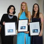 Three women posing for a photo while holding their awards.