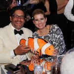 Adults posing for a photo with a stuffed clown fish