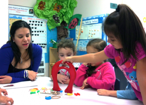 Teacher instructing young students to use a large magnet