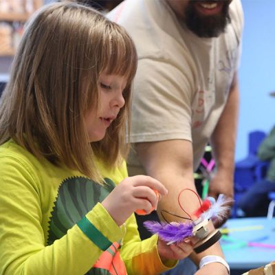 Young girl creating something with colorful feathers