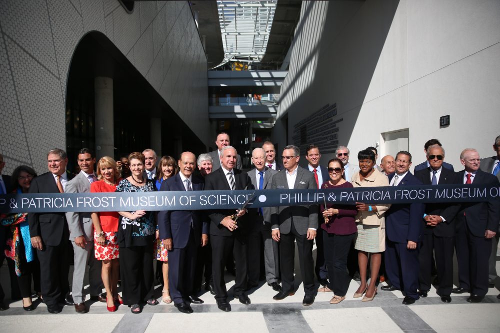 Group of adults posing for a photo behind a ribbon