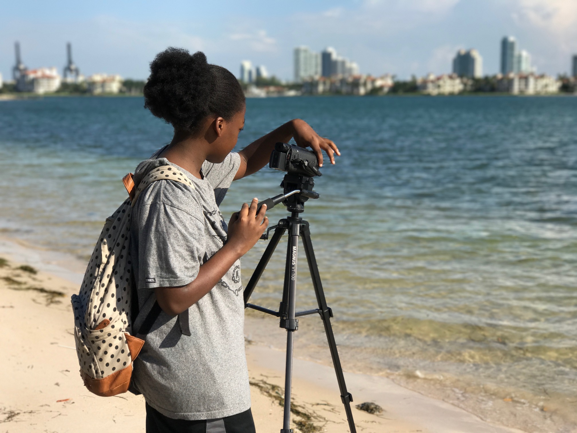 Young student operating a camera in front of the water