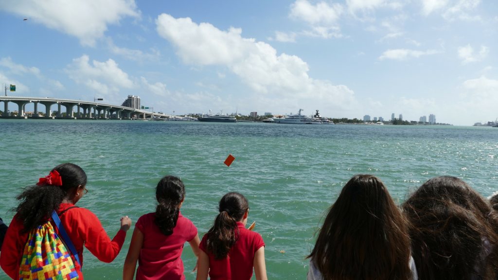 kids throw bay drift cards into the bay