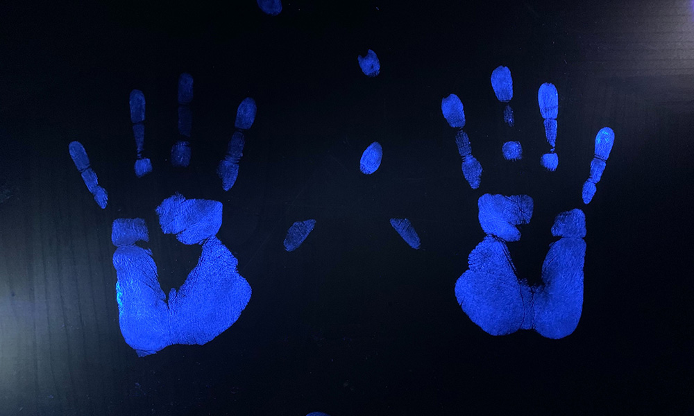 Two Glo Germ hand prints illuminated with uv light