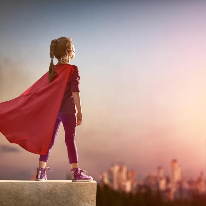 child wearing cape looks over city