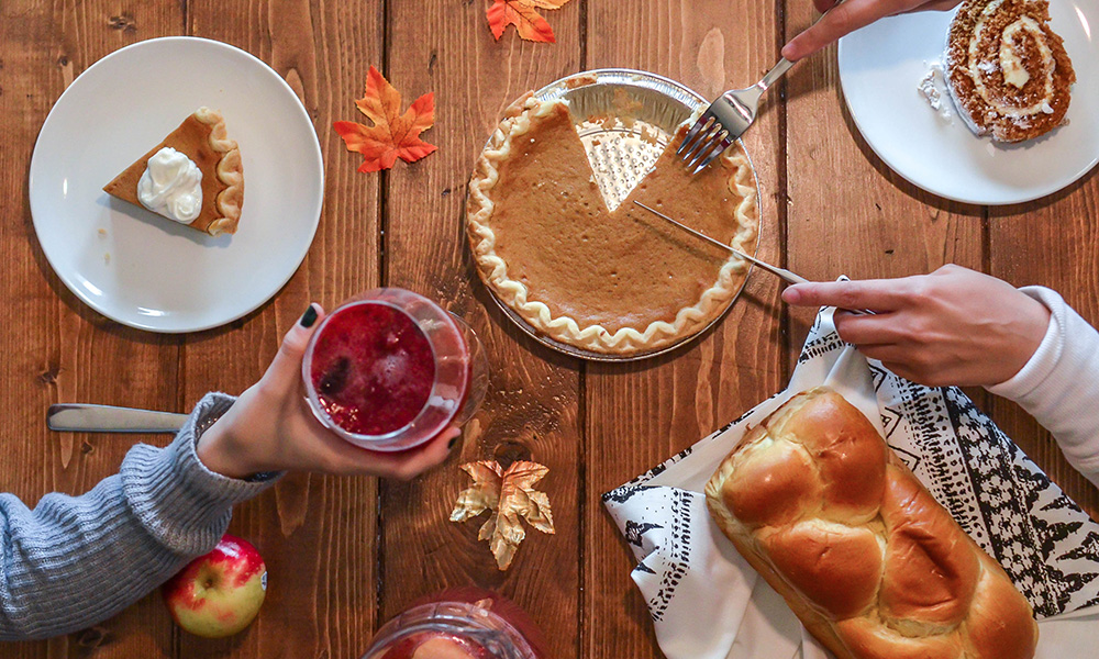 Assortment of traditional Thankgiving dishes including pumpkin pie and cranberry sauce.